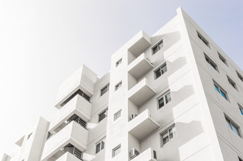 Fotografia de ângulo baixo de uma fachada de um edifício moderno branco sob um céu azul claro